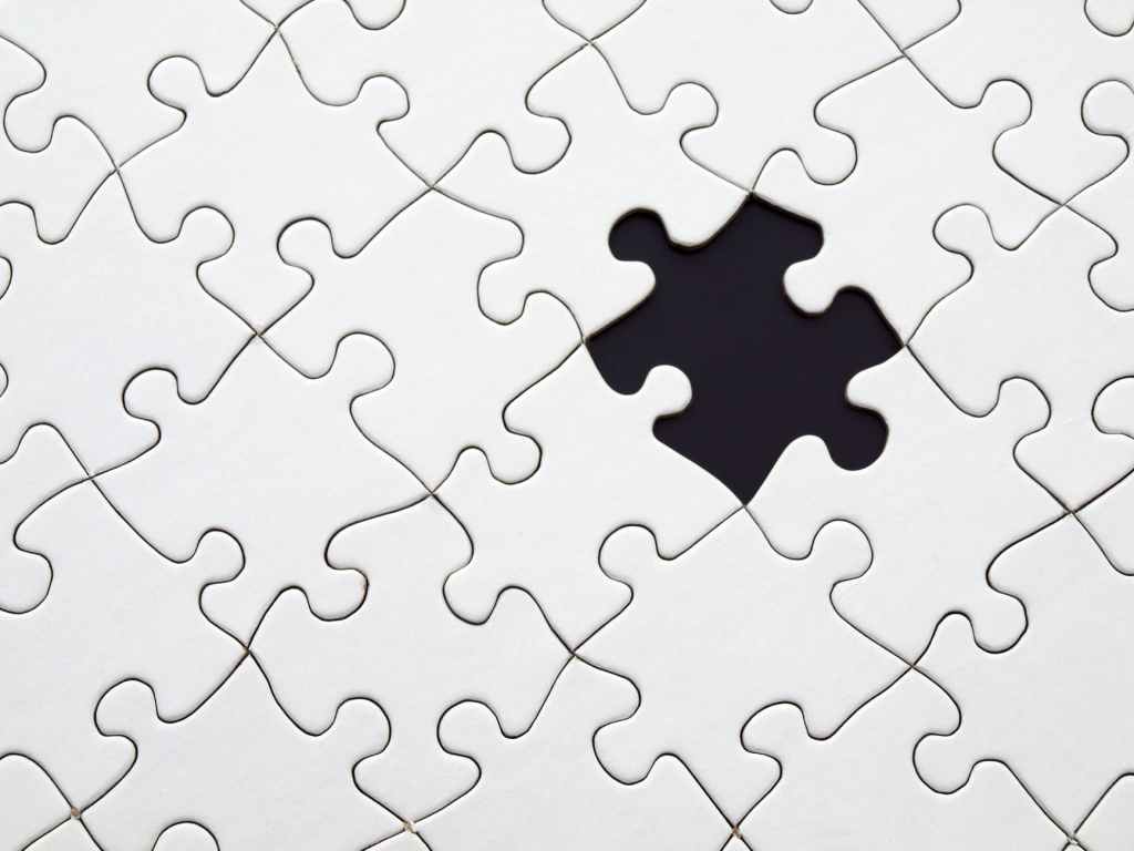 This image shows a jigsaw puzzle without image on it just white one piece is missing which makes it look like there is a black piece in a completely white puzzle