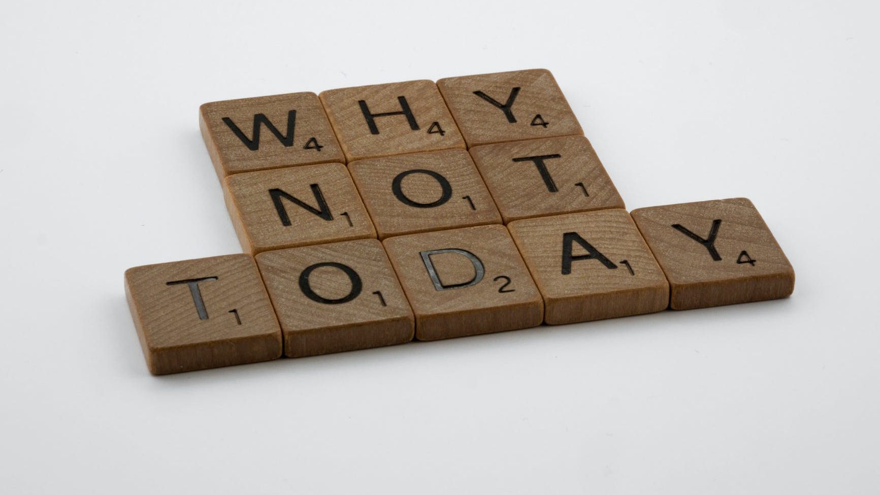 A photo of wooden Scrabble tiles. The words say@ Why not today