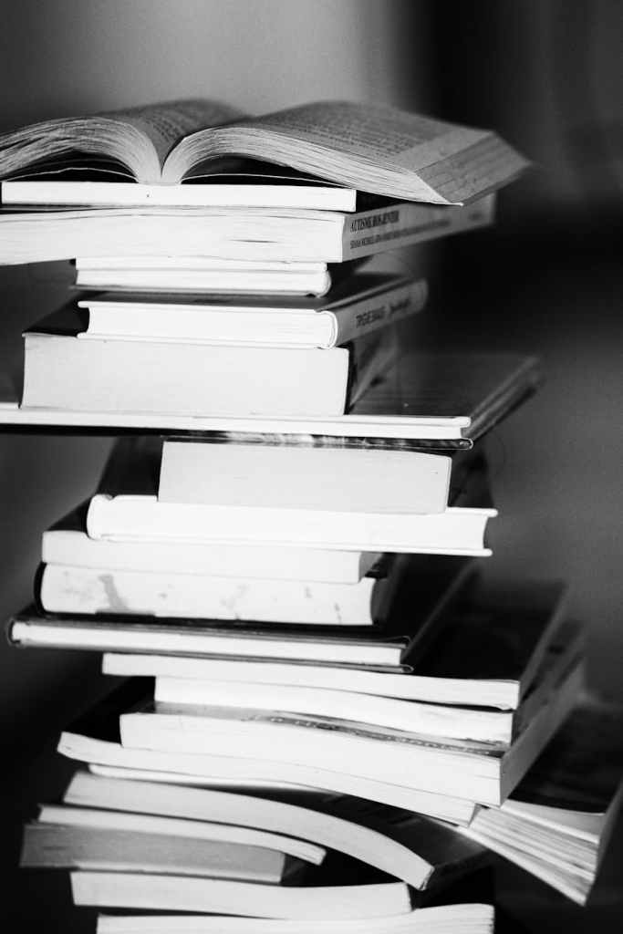 a black and white photo off a huge stack of books
