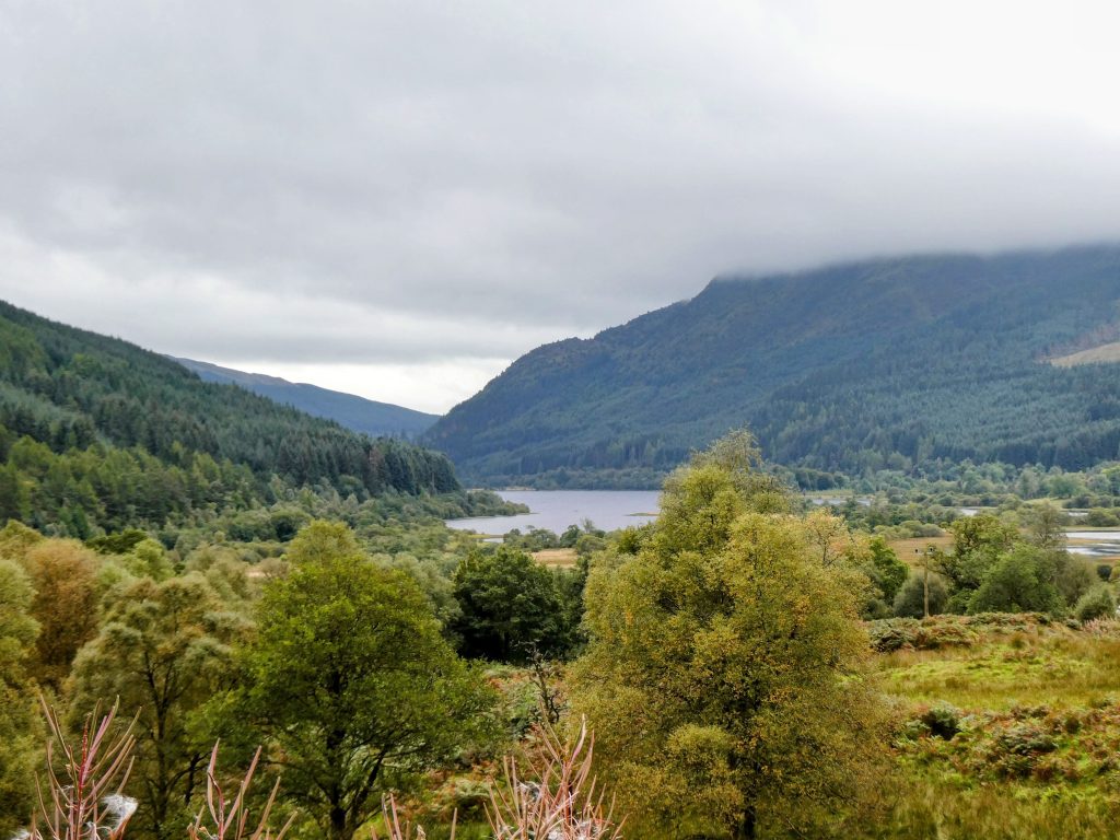 view over a loch surrounded by wooded hills
the clouds hang low and it is a dull day